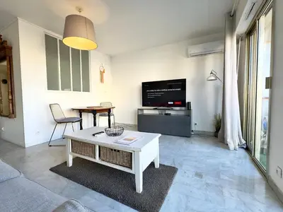 a living room with a couch and a table and a tv at L'Alexandra By SCLS Locations in Cannes