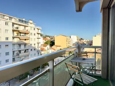 a balcony with two chairs and a view of a city at L'Alexandra By SCLS Locations in Cannes