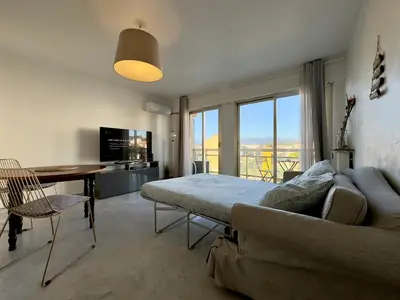 a living room with a bed and a table and a couch at L'Alexandra By SCLS Locations in Cannes