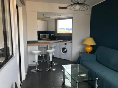 a living room with a blue couch and a kitchen at Esterel Terrasses, roof top front de mer, parking payant in Cannes