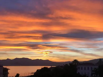 a sunset over a body of water with mountains at Esterel Terrasses, roof top front de mer, parking payant in Cannes