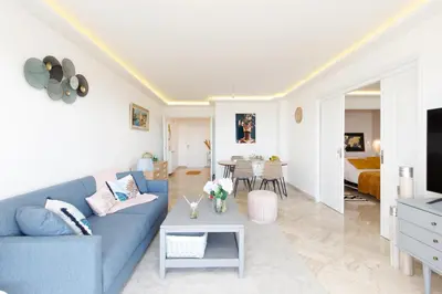a living room with a blue couch and a table at Suite Riviera - Sea View - Clim - 50M Plage - Residence de standing - Spacieux 180 M2 - Parking in Cannes
