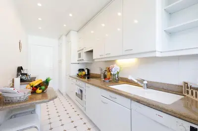 a white kitchen with white cabinets and a sink at Suite Riviera - Sea View - Clim - 50M Plage - Residence de standing - Spacieux 180 M2 - Parking in Cannes