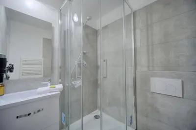 a bathroom with a shower with a glass door at IMMOGROOM - sea view - Pool - Terrace - Parking - Wifi - AC in Cannes