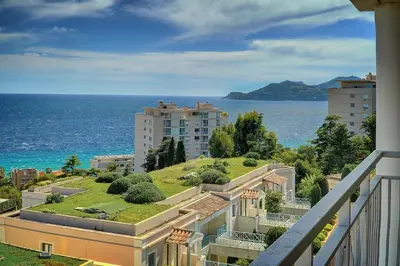 a building with a grassy hill next to the ocean at IMMOGROOM - sea view - Pool - Terrace - Parking - Wifi - AC in Cannes