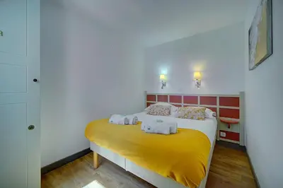 a bedroom with a yellow bed with towels on it at IMMOGROOM - 2 Rooms - Renovated - Pool - Parking - Air conditioning - in Cannes