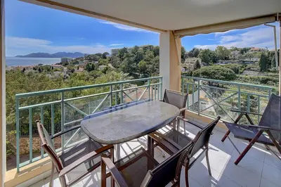 a table and chairs on a balcony with a view of the ocean at IMMOGROOM - 2 Rooms - Renovated - Pool - Parking - Air conditioning - in Cannes
