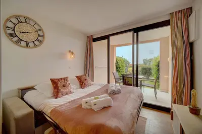 a bedroom with a bed with a clock on the wall at IMMOGROOM - 2 Rooms renovated - Pool - Terrace - Garden - Parking - in Cannes
