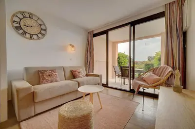 a living room with a couch and a clock on the wall at IMMOGROOM - 2 Rooms renovated - Pool - Terrace - Garden - Parking - in Cannes