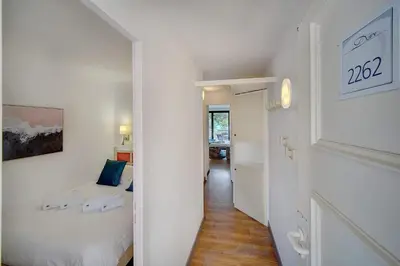 a white bedroom with a bed and a hallway at IMMOGROOM - 2 Rooms - Renovated - Pool - Air conditioning - Parking - Wifi in Cannes