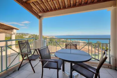 a balcony with a table and chairs and the ocean at IMMOGROOM - 2 Rooms sea view - Swimming pool - Terrace - Parking - AC in Cannes
