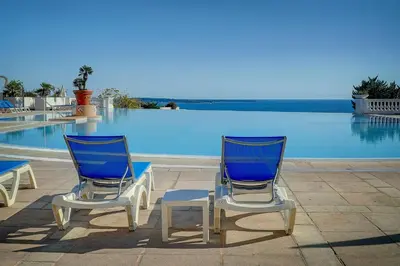 two blue and white chairs next to a swimming pool at IMMOGROOM - 2 Rooms sea view - Swimming pool - Terrace - Parking - AC in Cannes