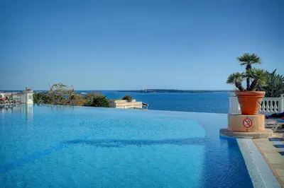 a large swimming pool next to a body of water at IMMOGROOM - 2 Rooms sea view - Renovated - Pool - Terrace - Parking - AC in Cannes