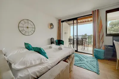 a bedroom with a couch and a clock on the wall at IMMOGROOM - 2 Rooms sea view - Renovated - Pool - Terrace - Parking - AC in Cannes