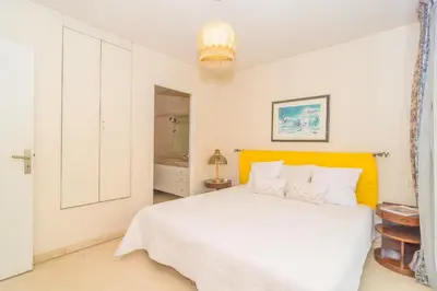 a bedroom with a white bed and a yellow headboard at Cannes Stunning sea and old town view for our full comfort 3 BR with balcony by Olam Properties in Cannes