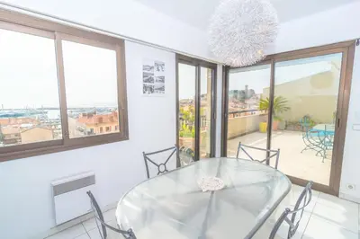 a dining room with a glass table and windows at Cannes Stunning sea and old town view for our full comfort 3 BR with balcony by Olam Properties in Cannes