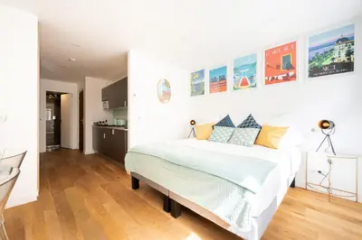 a white bedroom with a bed and a kitchen at Superbes studios entièrement rénovés - 50m croisette in Cannes