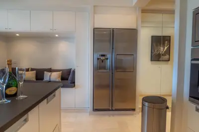 a kitchen with a stainless steel refrigerator and a couch at Cannes Croisette Superbe 3P front de mer in Cannes