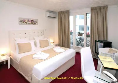 a hotel room with a large bed and a balcony at HOTEL PALM BEACH in Cannes