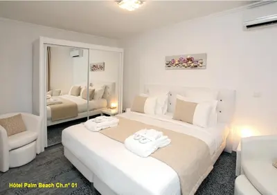 a white bedroom with two beds and a mirror at HOTEL PALM BEACH in Cannes