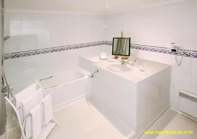 a white bathroom with a sink and a bath tub at HOTEL PALM BEACH in Cannes