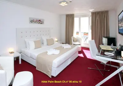 a hotel room with a large white bed and a desk at HOTEL PALM BEACH in Cannes