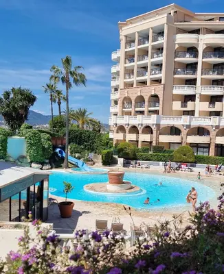 a hotel with a swimming pool in front of a building at Magnifique T2 Climatisation - Grande Terrasse, Piscine et apercu Mer in Cannes