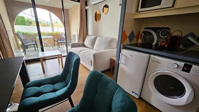 a living room with a washing machine and chairs at Magnifique T2 Climatisation - Grande Terrasse, Piscine et apercu Mer in Cannes