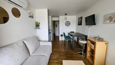 a living room with a couch and a table at Magnifique T2 Climatisation - Grande Terrasse, Piscine et apercu Mer in Cannes