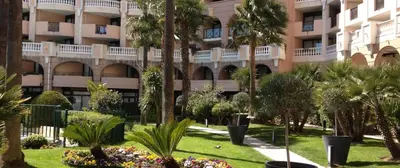 a large apartment building with palm trees in a park at Magnifique T2 Climatisation - Grande Terrasse, Piscine et apercu Mer in Cannes