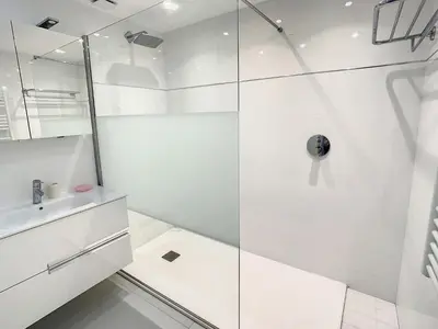 a white bathroom with a shower and a sink at Appartements de Standing Cannes Centre in Cannes