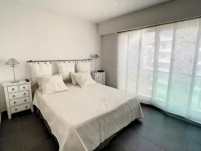a white bedroom with a bed and a window at Appartements de Standing Cannes Centre in Cannes