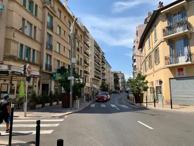 a street with a car driving down a city street at Cannes Centre, T2 moderne rénové, balcon clim&Wifi in Cannes