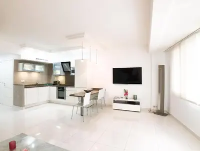 a white living room with a table and a kitchen at 2 pièces Luxueux en face du Martinez et Croisette in Cannes