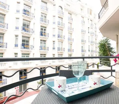 a table with a glass of wine on a balcony at 2 pièces Luxueux en face du Martinez et Croisette in Cannes