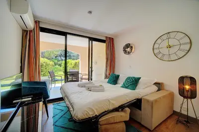 a bedroom with a bed and a clock on the wall at IMMOGROOM - 2 Rooms - Renovated - Pool - AC - Parking - Garden in Cannes