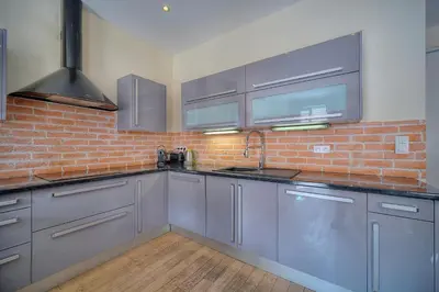 a kitchen with gray cabinets and a brick wall at 2 chambres BALCON, FELIX FAURE-COEUR DE CANNES A2B022 in Cannes