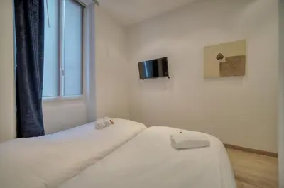 two beds in a room with a tv on the wall at 2 chambres BALCON, FELIX FAURE-COEUR DE CANNES A2B022 in Cannes