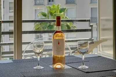 a bottle of wine sitting on a table with two glasses at Lumineux Studio TERRASSE, Rouaze-MARTINEZ CARLTON A0B132 in Cannes