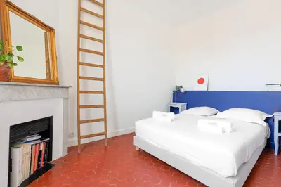 a bedroom with a bed and a ladder next to a fireplace at IMMOGROOM - Bright flat - near shops - CONGRESSBEACHES in Cannes