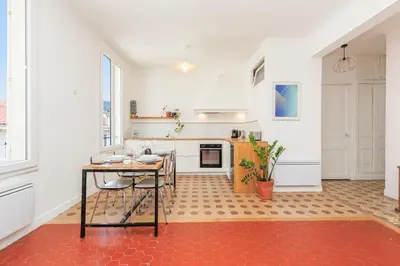 a large white kitchen with a table and a counter at IMMOGROOM - Bright flat - near shops - CONGRESSBEACHES in Cannes