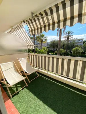 two chairs and an umbrella on a balcony at Superb Apartment In Cannes With Magnificent View ! in Cannes