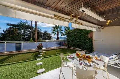 a patio with a table and chairs and a lawn at 2-Br Luxury Apartment with Sea View and Pool in Cannes