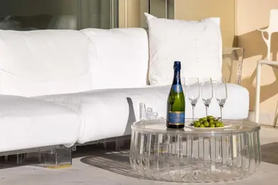 a bottle of wine on a table next to a couch at 2-Br Luxury Apartment with Sea View and Pool in Cannes