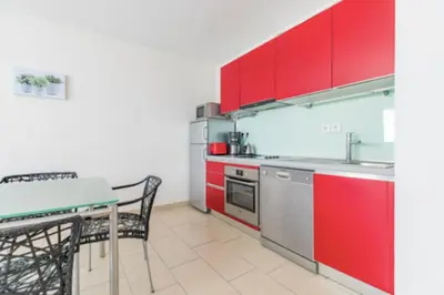 a kitchen with red cabinets and a table and chairs at Bright Apartment In The Heart Of Cannes in Cannes