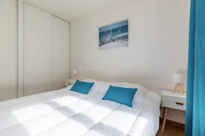 a white bed with blue pillows in a bedroom at Bright Apartment In The Heart Of Cannes in Cannes