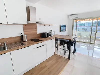 a kitchen with white cabinets and a wooden counter top at Studio luxueux et spacieux avec terrasse in Cannes