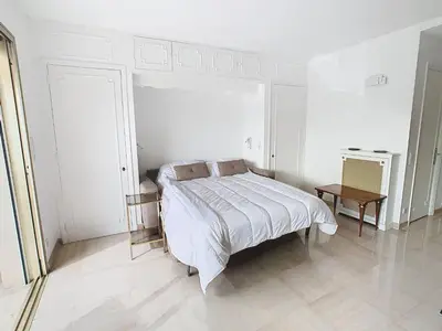 a white bedroom with a bed and a table at Studio luxueux et spacieux avec terrasse in Cannes