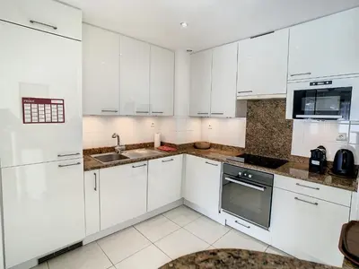 a white kitchen with white cabinets and a sink at Studio luxueux et spacieux avec terrasse in Cannes