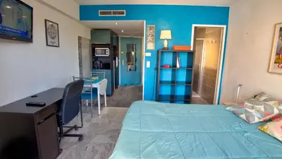 a bedroom with a bed and a desk and a kitchen at 3 StarsStudio54 23 Ave Laugier100m Plages Mistral in Cannes